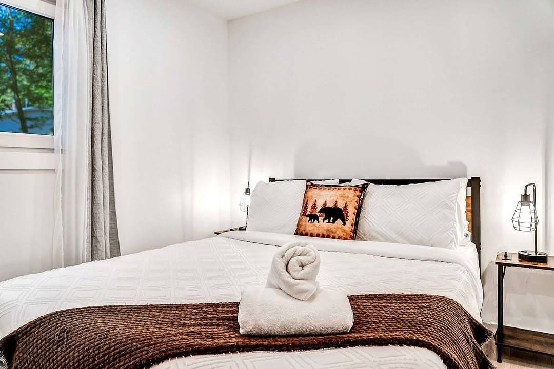 Hotel-style vacation rental bedroom with rolled towel and bear accent pillow after Forteca turnover